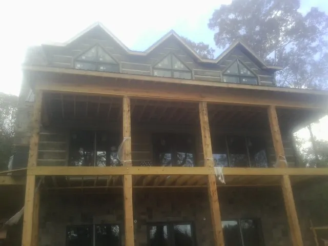 Dormers and porch framing on a large log home under construction — Roof Coating work by our crew in Whitney Point
