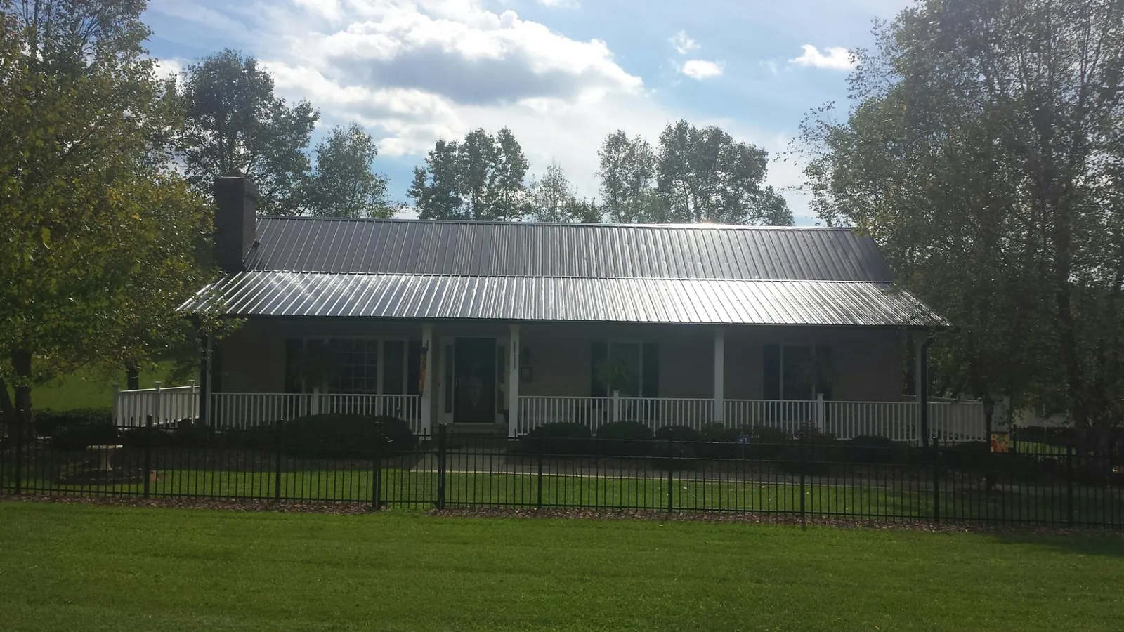 Gray metal roof on a brick ranch with a full width front porch — Gutter Guard Installation work by our crew in Whitney Point